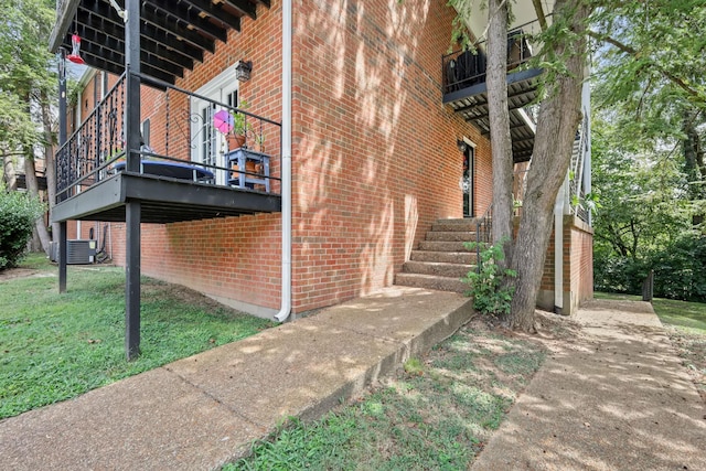 view of side of home with a yard, central AC unit, and brick siding