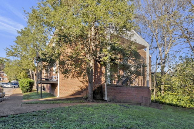 view of home's exterior with a yard, brick siding, and stairway