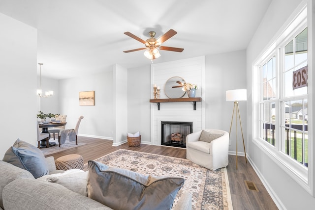 living room with ceiling fan, dark hardwood / wood-style flooring, a large fireplace, and a wealth of natural light