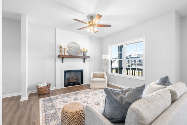 living room featuring a large fireplace, wood-type flooring, and ceiling fan