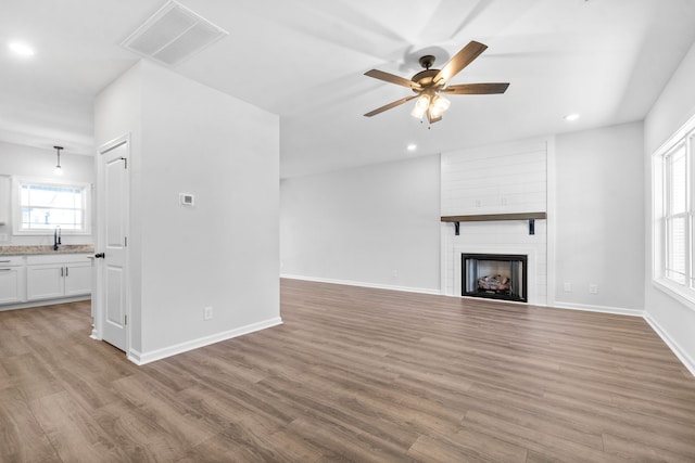 unfurnished living room featuring a fireplace, a wealth of natural light, and light hardwood / wood-style floors