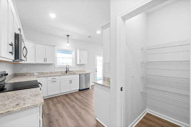 kitchen with light stone counters, sink, light hardwood / wood-style flooring, white cabinetry, and appliances with stainless steel finishes