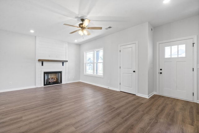 unfurnished living room with a large fireplace, ceiling fan, and hardwood / wood-style floors