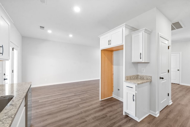 kitchen featuring stainless steel dishwasher, white cabinets, dark hardwood / wood-style flooring, and light stone counters