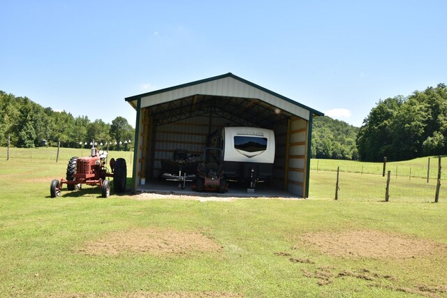 view of outdoor structure featuring a carport, a yard, and a rural view