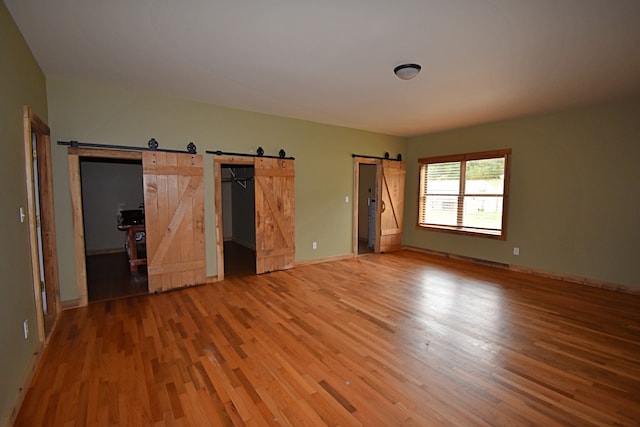 unfurnished bedroom featuring a barn door and hardwood / wood-style floors