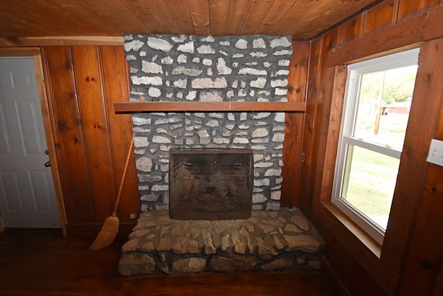 interior details featuring wooden walls, a stone fireplace, wood ceiling, and wood-type flooring