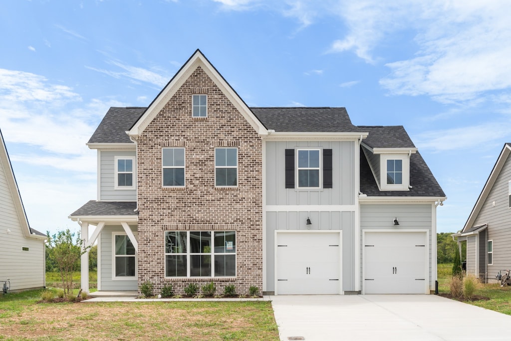 view of front of property with concrete driveway, a shingled roof, board and batten siding, and brick siding