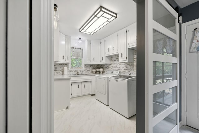 laundry room with cabinet space, a barn door, washing machine and clothes dryer, marble finish floor, and a sink