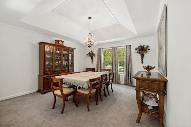 carpeted dining room with a chandelier, a raised ceiling, and crown molding