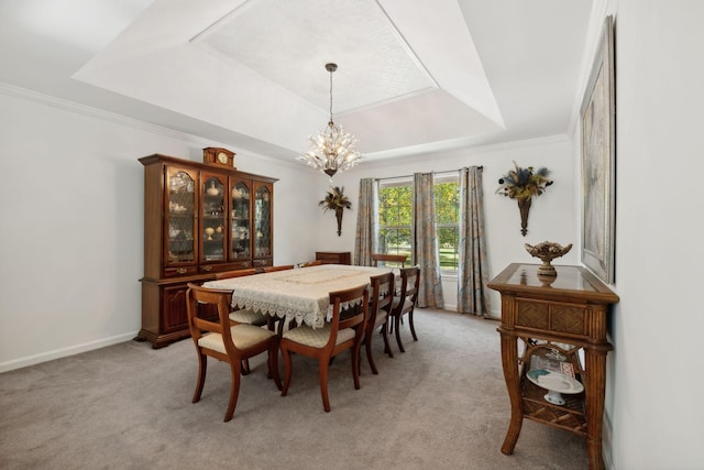 dining space with a tray ceiling, light colored carpet, ornamental molding, a chandelier, and baseboards