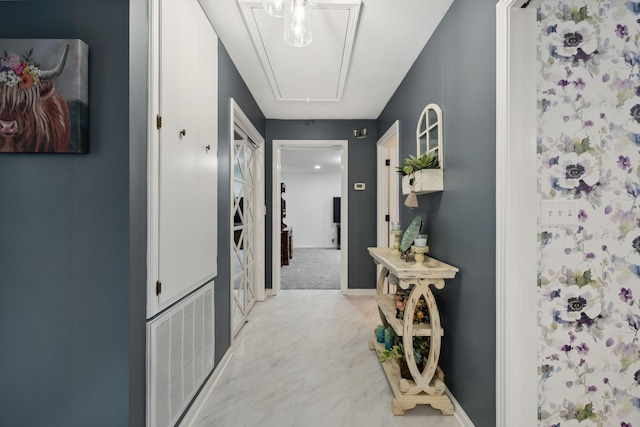 hallway featuring attic access, visible vents, and baseboards