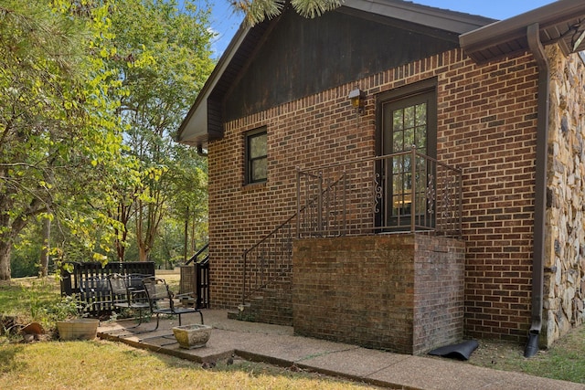 view of side of property featuring brick siding and a patio area