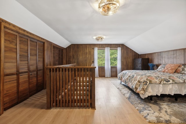 bedroom with lofted ceiling, light wood finished floors, and wood walls