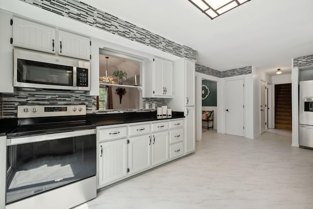 kitchen with dark countertops, white cabinetry, appliances with stainless steel finishes, and backsplash