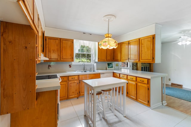 kitchen featuring decorative light fixtures, a kitchen breakfast bar, kitchen peninsula, sink, and ceiling fan