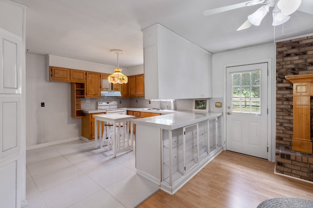 kitchen with hanging light fixtures, electric range, ceiling fan, kitchen peninsula, and a breakfast bar area