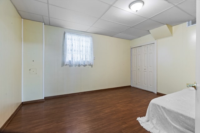 bedroom with a closet, dark hardwood / wood-style flooring, and a drop ceiling