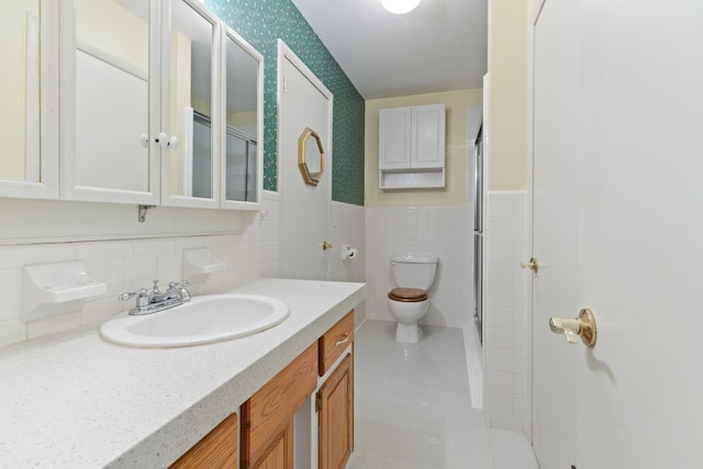 bathroom with toilet, a shower with door, vanity, tasteful backsplash, and tile walls