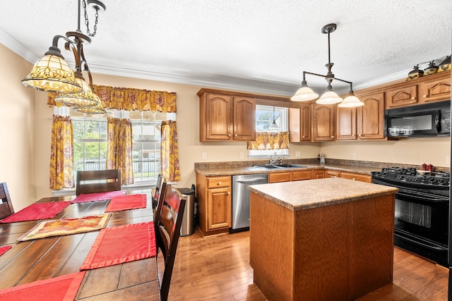 kitchen with light wood-type flooring, decorative light fixtures, black appliances, a kitchen island, and sink