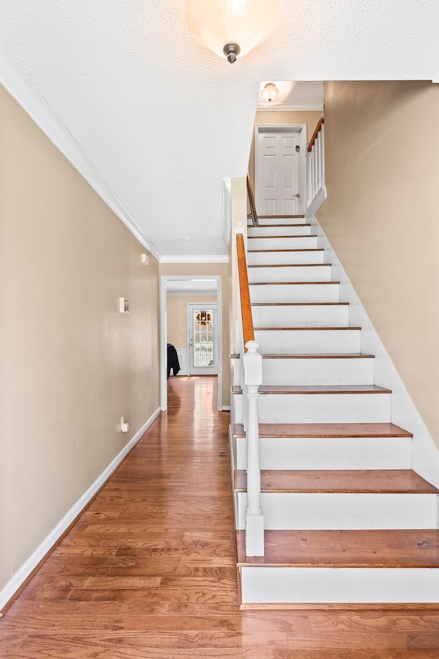 staircase with crown molding and hardwood / wood-style flooring