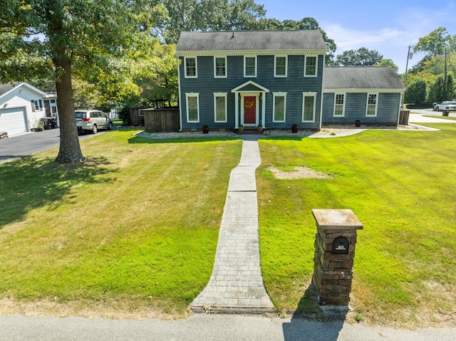 colonial-style house featuring a garage and a front lawn