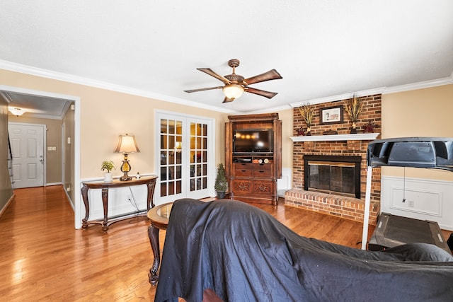 living room with crown molding, wood-type flooring, and a brick fireplace