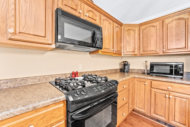 kitchen featuring light wood-type flooring, black appliances, and a textured ceiling