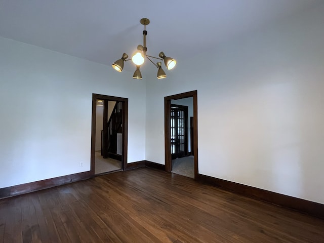 unfurnished room featuring dark wood-type flooring and a notable chandelier