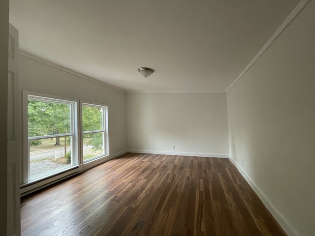 empty room with ornamental molding, dark wood-type flooring, and a baseboard heating unit