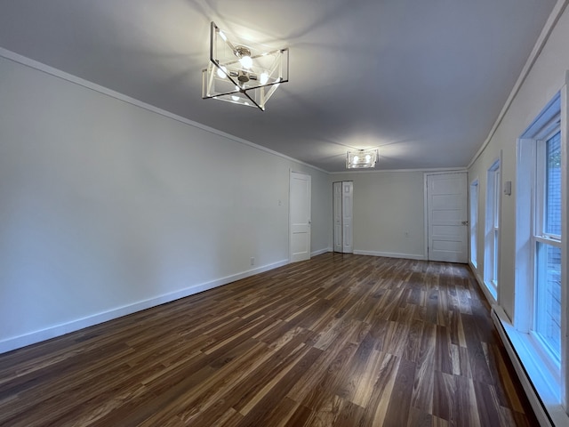 unfurnished room with ornamental molding, baseboard heating, dark hardwood / wood-style floors, and an inviting chandelier