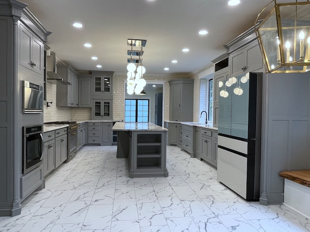 kitchen featuring wall chimney range hood, pendant lighting, a kitchen island, and gray cabinets