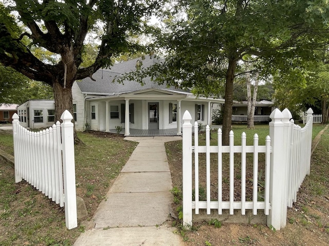 bungalow-style house with covered porch, a fenced front yard, a front lawn, and roof with shingles