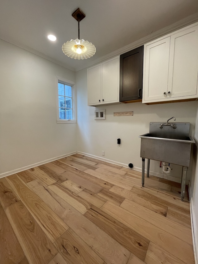 laundry room with hookup for a washing machine, cabinets, ornamental molding, and light hardwood / wood-style floors