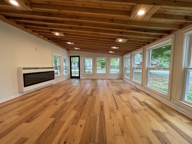 unfurnished living room with wood ceiling, lofted ceiling, a healthy amount of sunlight, and light hardwood / wood-style floors