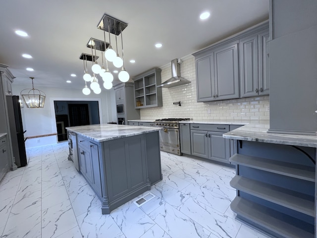 kitchen with gray cabinets, a center island, an inviting chandelier, wall chimney exhaust hood, and high end stove