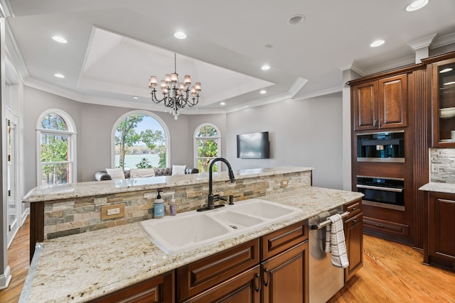 kitchen with light hardwood / wood-style flooring, tasteful backsplash, stainless steel appliances, sink, and a chandelier