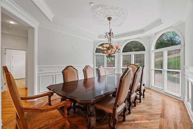 dining room with ornamental molding, a notable chandelier, and light wood-type flooring