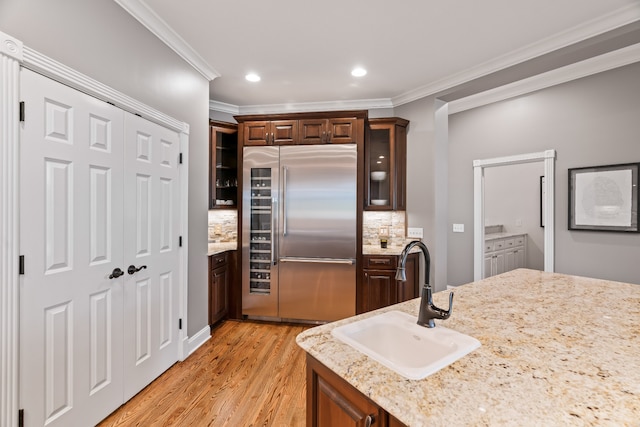 kitchen featuring ornamental molding, stainless steel built in fridge, tasteful backsplash, sink, and light hardwood / wood-style floors