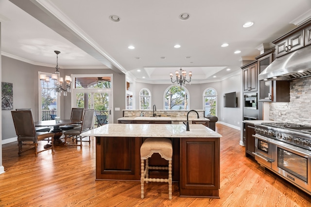 kitchen featuring a center island with sink, a notable chandelier, appliances with stainless steel finishes, and light hardwood / wood-style floors