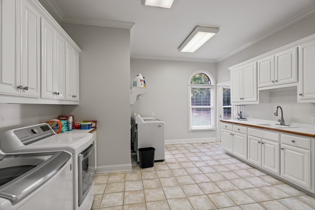 laundry room featuring cabinets, light tile patterned floors, washing machine and clothes dryer, ornamental molding, and sink