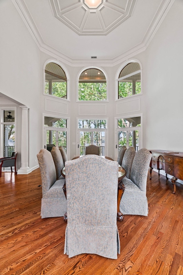 living room with ornamental molding, a towering ceiling, and hardwood / wood-style flooring