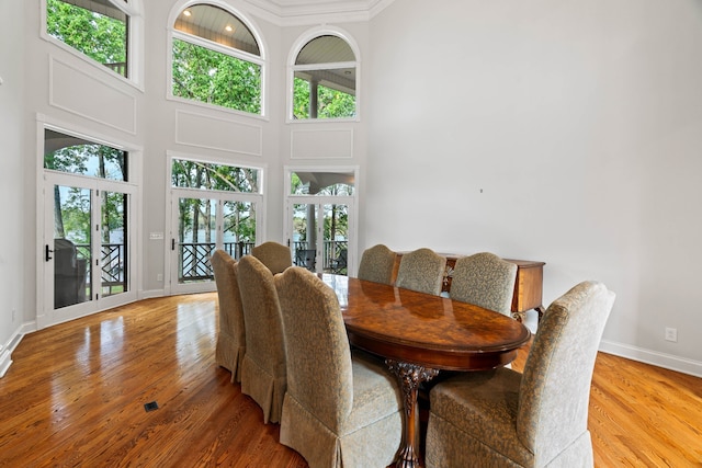 dining area featuring a towering ceiling, french doors, crown molding, and light hardwood / wood-style floors