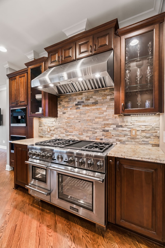 kitchen featuring crown molding, double oven range, dark hardwood / wood-style floors, extractor fan, and dark brown cabinetry