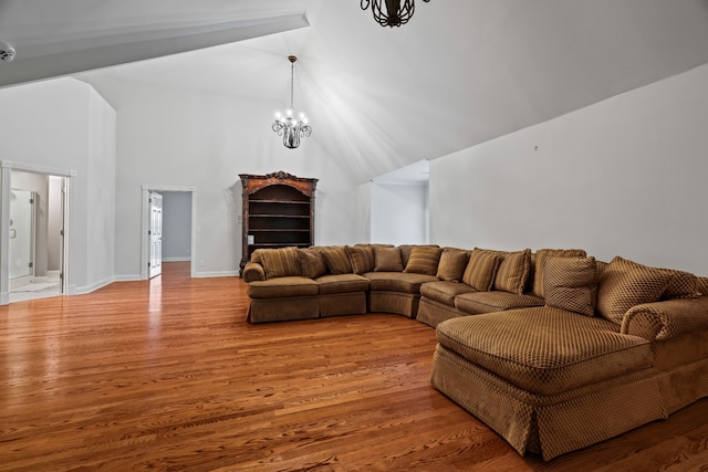 living room with high vaulted ceiling, wood-type flooring, and an inviting chandelier