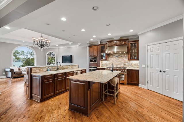 kitchen with stainless steel appliances, an island with sink, sink, a breakfast bar, and light hardwood / wood-style floors