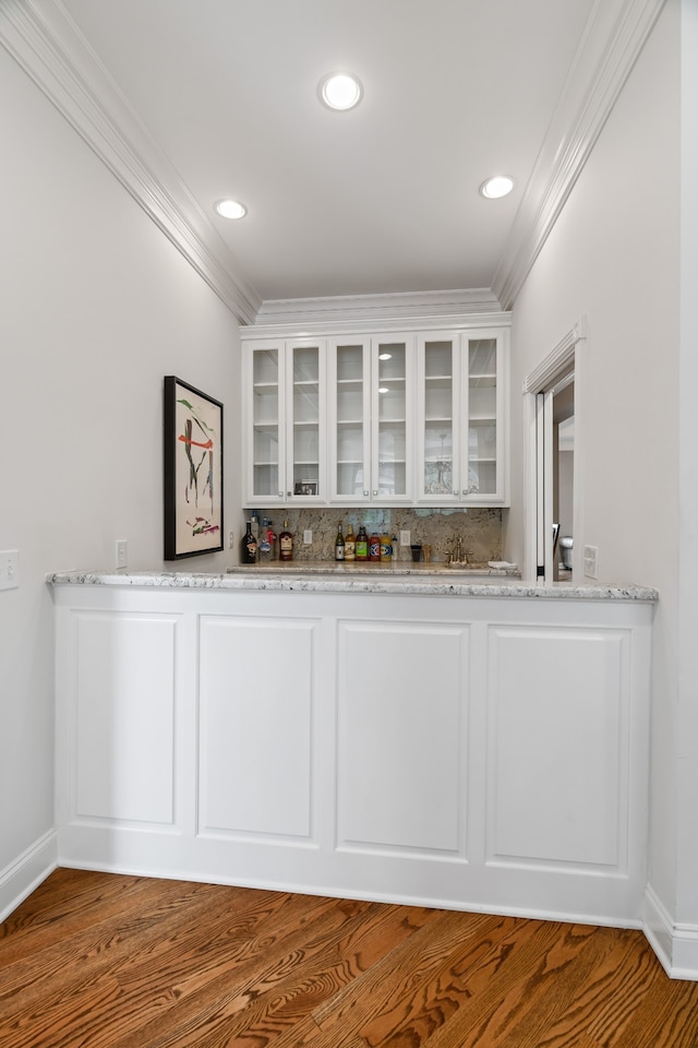 bar with hardwood / wood-style flooring, light stone counters, and white cabinetry