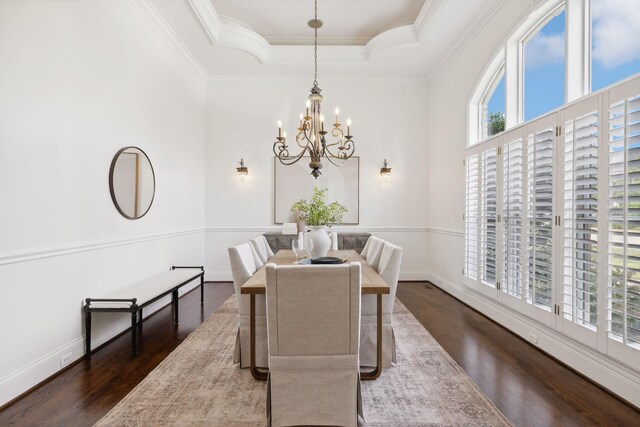 dining area featuring dark wood-type flooring, a notable chandelier, a raised ceiling, and crown molding