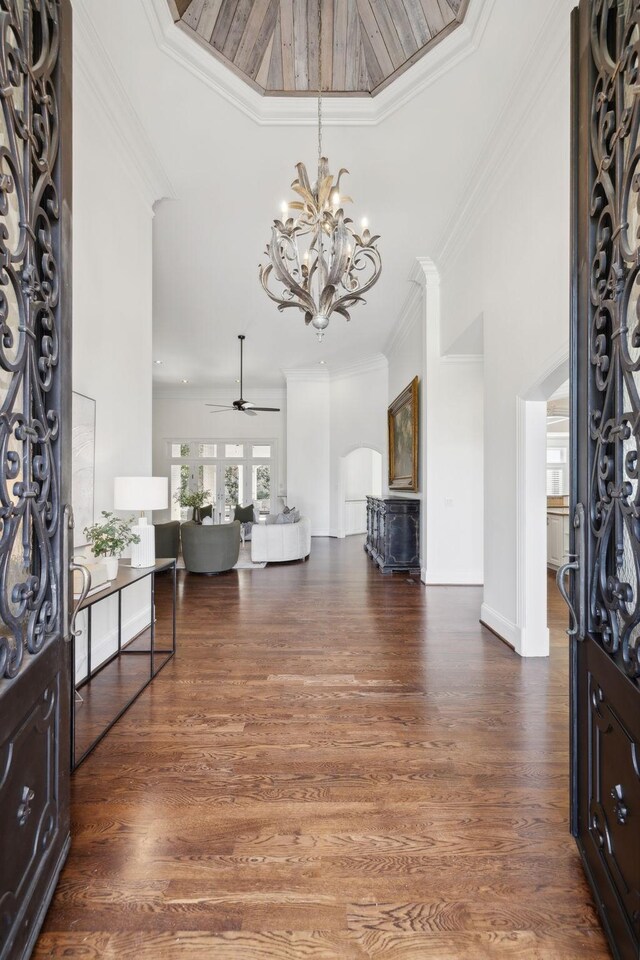 interior space featuring ceiling fan with notable chandelier, dark wood-type flooring, and ornamental molding