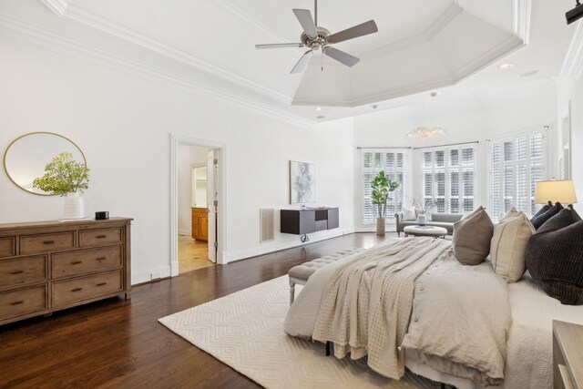 bedroom with a tray ceiling, dark wood-type flooring, ensuite bath, ornamental molding, and ceiling fan